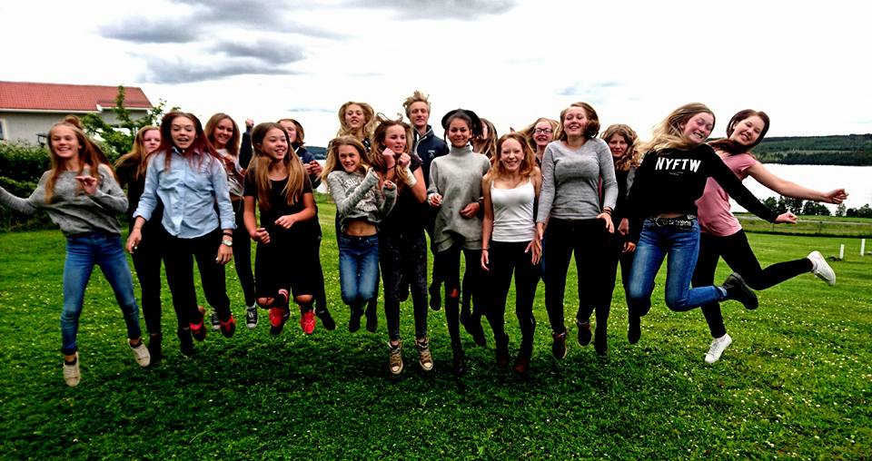 Femton glada deltagare på islandhästlägret på gräsmattan hoppar unsiont upp i luften