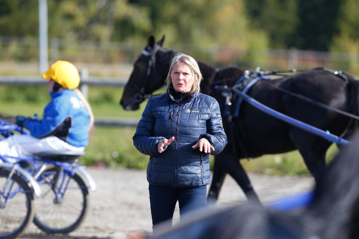 Hästlärare instruerar travelever på körbana utomhus