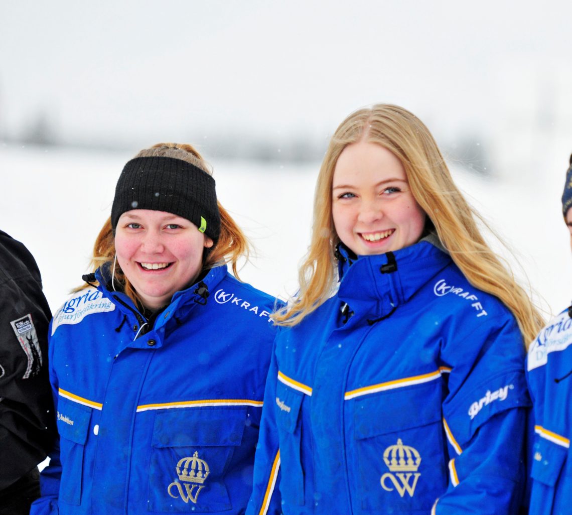 Två gymnasielever utomhus i vinterväder iklädda Wångens blå travdressar.