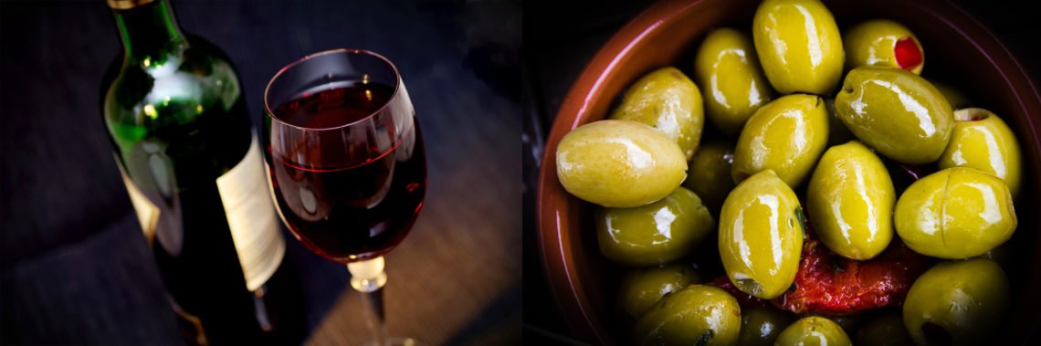 Vinprovning flaska rött vin, glas med rött vin och en skål gröna oliver
