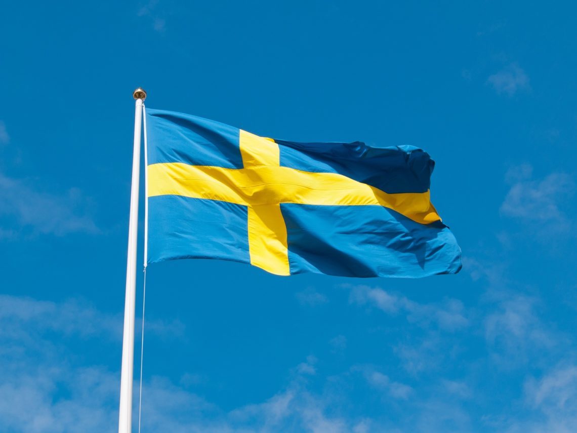 Svensk flagga vajar mot blå himmel symboliserar nationaldagsfirande